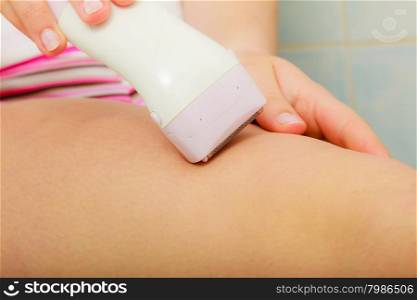 Hygiene skin body care concept. Hair removal. Closeup woman shaving legs with electric shaver depilator in bathroom