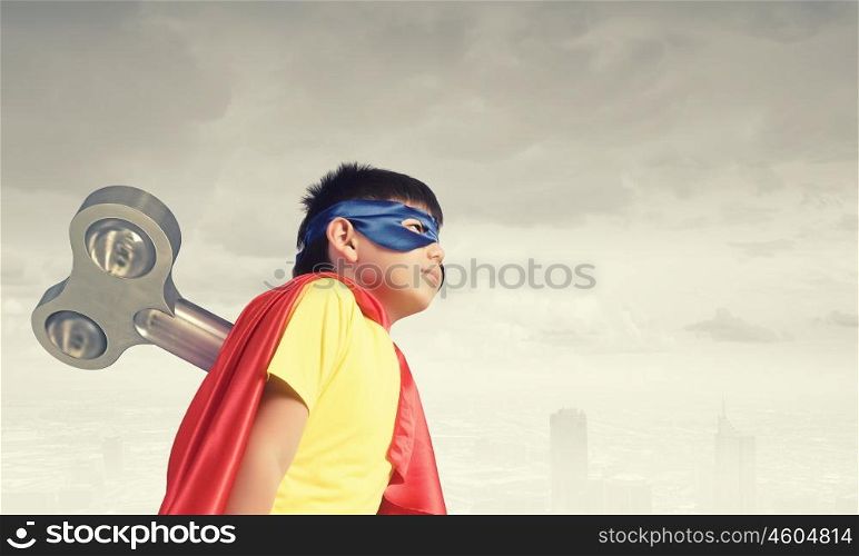 Hyperactive super child. Little super active boy with key on back wearing super hero costume