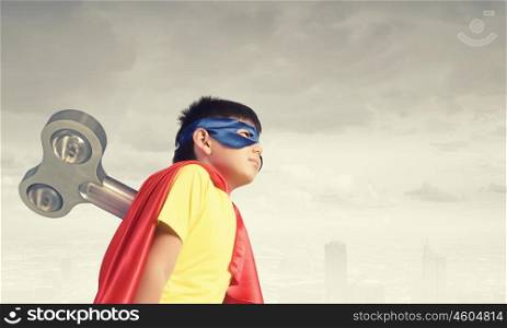 Hyperactive super child. Little super active boy with key on back wearing super hero costume