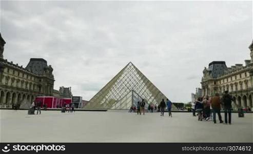Hyperlapse shot of people walking outside Louvre Museum and taking shots of Pyramid. The most famous museum in the world