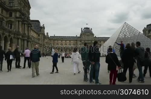 Hyperlapse shot of tourists and visitors walking around the Louvre area and coming into the Pyramid, main entrance of the museum