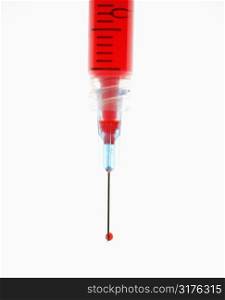 Hypodermic needle filled with red liquid.