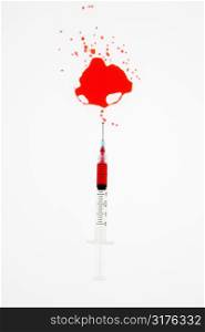 Hypodermic needle with red liquid sprayed on white background.