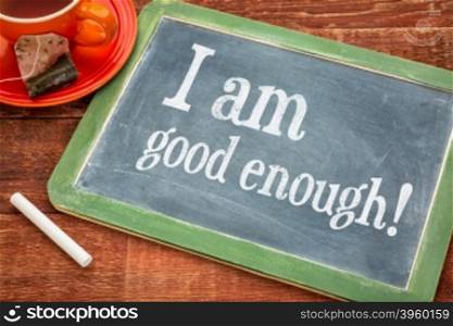 I am good enough - positive affirmation on a slate blackboard with chalk and cup of tea