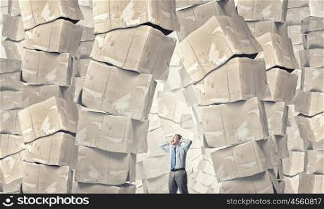I did all the hard work. Young businessman and stack of carton boxes behind him