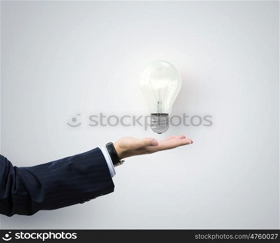 I have interesting idea. Businessman hand holding light bulb in palm