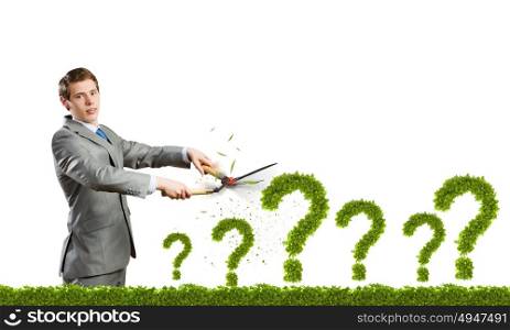 I have question. Young businessman cutting plant shaped like question mark
