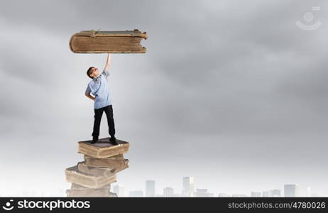 I like reading. Boy of school age in glasses standing on pile of books