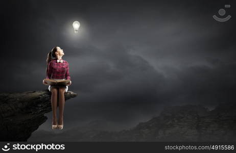 I like reading!. Young beautiful lady sitting on rock edge and reading book