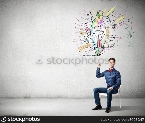 I&rsquo;ve got an idea!. Young funny guy sitting in chair and pointing upwards