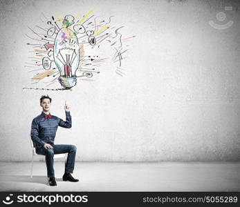 I&rsquo;ve got an idea!. Young funny guy sitting in chair and pointing upwards