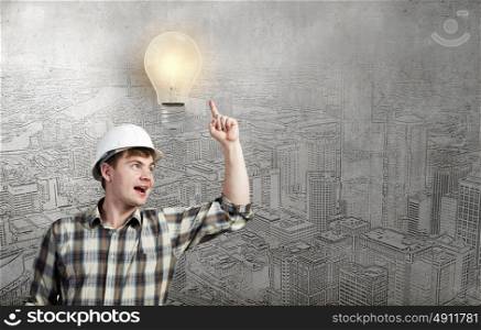 I&rsquo;ve got an idea!. Young man builder pointing at light bulb. Idea concept