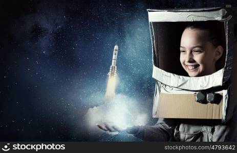 I will explore space. Cute kid girl with carton helmet on head dreaming to become astronaut
