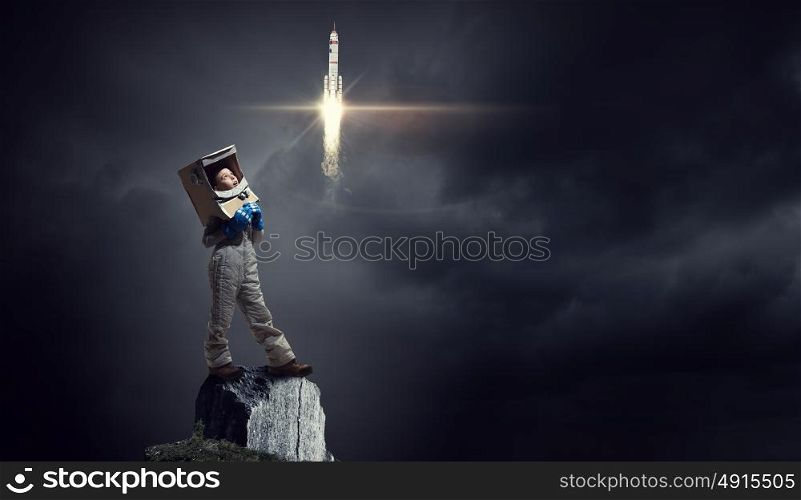 I will explore space. Cute kid girl with carton helmet on head dreaming to become astronaut