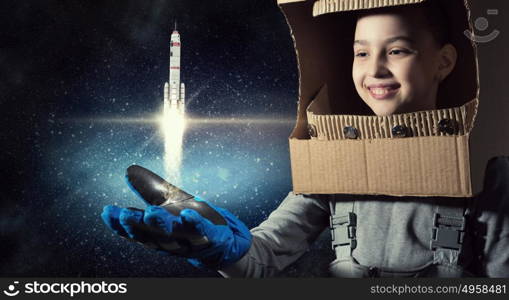 I will explore space. Cute kid girl with carton helmet on head dreaming to become astronaut