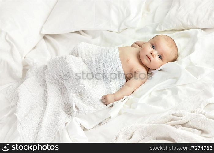 Iamge of a charming toddler lying on the bright sheet