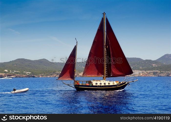 Ibiza Red sails sailboat in Sa Talaia coast of Balearic Islands