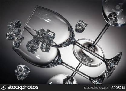 ice and empty wineglasses on color background