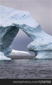 Ice arch in iceberg as a gate with a view of beautiful light in Antarctica