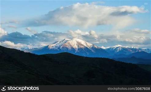 Ice capped mountain peaks panorama landscape with big white clouds and blue sky