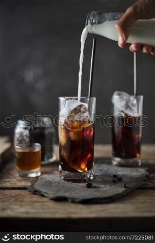 Ice coffee in a tall glass on wooden table.