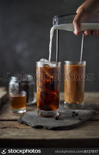 Ice coffee in a tall glass on wooden table. 