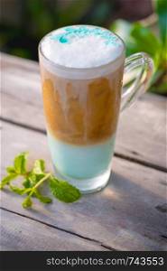 Ice coffee mint in glass with mint leaves on wooden table background.