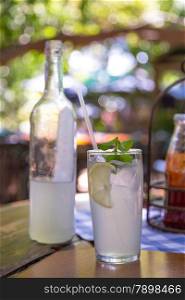 Ice cold lemonade served with mint leaves on a hot summer day under a tree shade