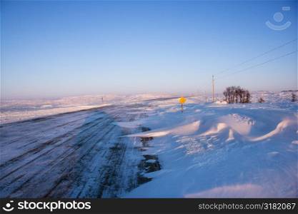 Ice covered road and snowy rural landscape.