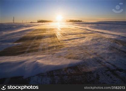 Ice covered road with sun rising in distance.