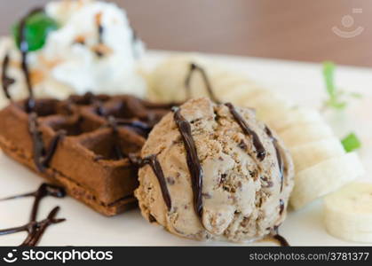 ice cream , banana , chocolate waffles with chocolate sauce and whipping cream