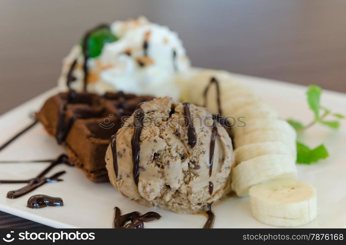 ice cream , banana , chocolate waffles with chocolate sauce and whipping cream