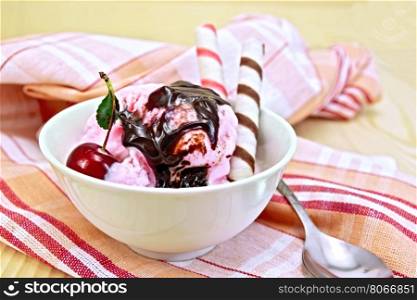 Ice cream cherry in a bowl, chocolate syrup and wafer rolls on a wooden boards background