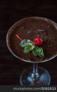 Ice cream chocolate dessert. Ice cream chocolate dessert decorated with cherry on dark brown background