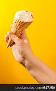 ice cream cone in hand on yellow background