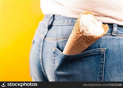 ice cream cone in jeans pocket on yellow background