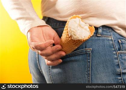 ice cream cone in jeans pocket on yellow background