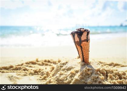 Ice cream cone on sand beach background / Melting ice cream on beach sea in summer hot weather ocean landscape nature outdoor vacation , ice cream chocolate