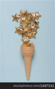 Ice cream cone with shiny golden stars on blue pastel background top view