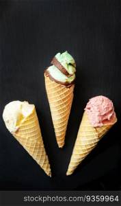 Ice cream in a waffle cone with different flavors on a black board. Vertical photo. Ice cream in a waffle cone with different flavors on a black board. Vertical photo.