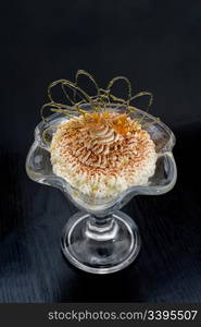 ice cream in glass bowl dusted with chocolate and decorated with caramel curl