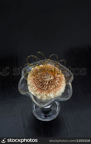 ice cream in glass bowl dusted with chocolate and decorated with caramel curl