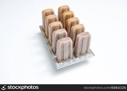 Ice cream lolly coffee in plastic molds on a white background with space for text. Summer dessert. Plastic molds with coffee homemade ice cream on white background with copy space. Cold dessert