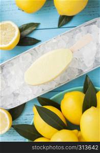Ice cream made from lemon frozen juice sherbet in still tray and raw lemons on blue background