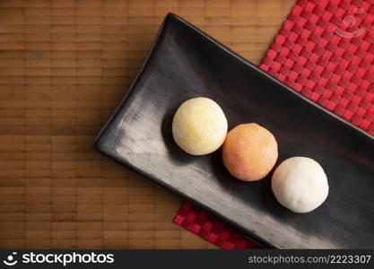Ice cream mini Mochis. Traditional Japanese dessert made from rice flour. Close up on bamboo surface. Top view. Copy space