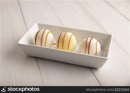 Ice cream Mochis with caramel  cajeta . Traditional Japanese dessert made from rice flour. Close up on white wooden surface. 