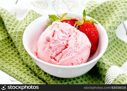 Ice cream strawberry in a white bowl with berries on a green napkin against a light wooden board