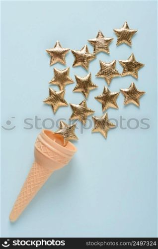 Ice cream sweet wafer cone with shiny golden stars on blue pastel background top view