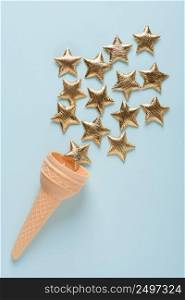 Ice cream sweet wafer cone with shiny golden stars on blue pastel background top view
