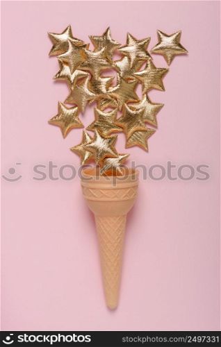 Ice cream sweet wafer cone with shiny golden stars on pink pastel background flatlay